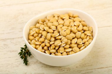 Ahşap arka plan üzerinde kapta çiğ beyaz fasulye