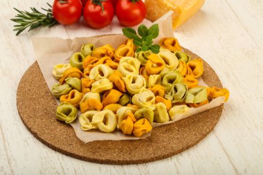 Fesleğenli - ahşap arka plan üzerinde yemek pişirmek için hazır çiğ tortellini