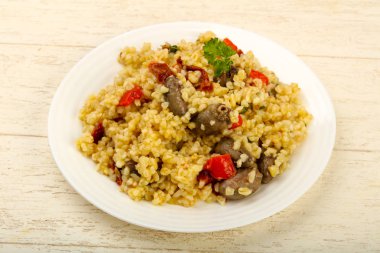 Bulgur tavuk kalpleri ve ahşap arka plan üzerinde kuru domates ile kase