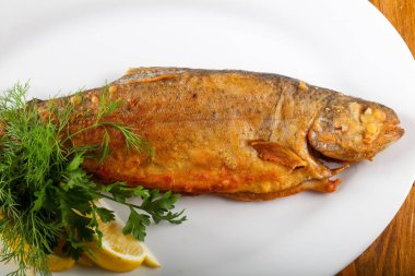 Kızarmış alabalık limon ve otlar ahşap arka plan üzerinde servis