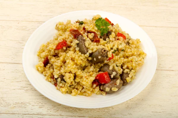 Bulgur tavuk kalpleri ve ahşap arka plan üzerinde kuru domates ile kase