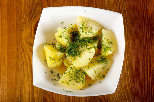 Ahşap arka plan üzerinde beyaz kase dereotu ile haşlanmış patates