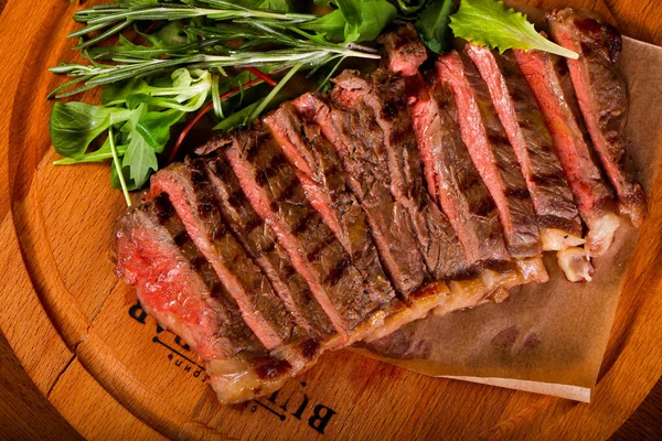 Beef steak with sauce and salad dressing over wooden background