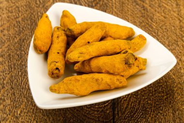 Tumeric kökü yığın kase ahşap arka plan üzerinde