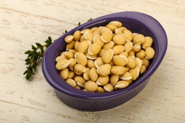 Ahşap arka plan üzerinde kapta çiğ beyaz fasulye