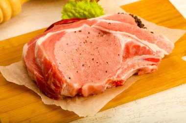 Çiğ Domuz pirzola ahşap arka plan üzerinde baharatlar ile