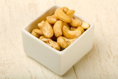 Kaju fıstığı yığın kase ahşap arka plan üzerinde