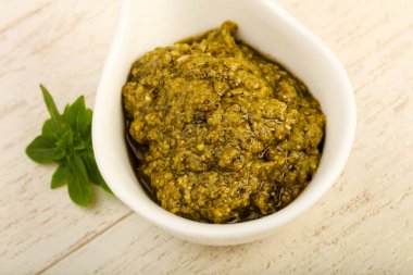 Fesleğenli pesto sos kapta ahşap arka plan üzerinde bırakır.