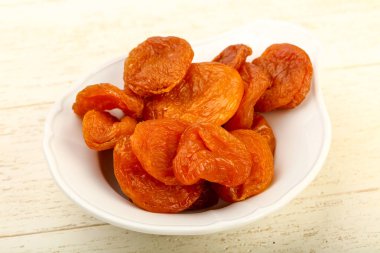 Ahşap arka plan üzerinde kase kuru kayısı yığın