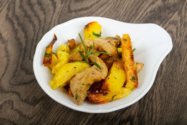 Domuz eti ile kızarmış patates biberiye ahşap arka plan üzerinde hizmet.