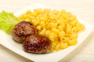 Beyaz tabak içinde pirzola ile makarna makarna