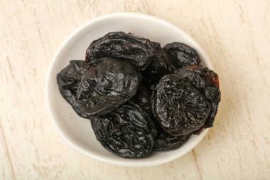 Ahşap arka plan üzerinde beyaz kase kuru erik yığın