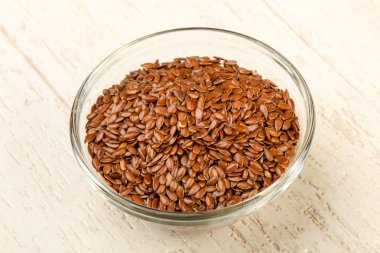 Kızartma keten tohumları ahşap arka planda kasede yığılıyor.