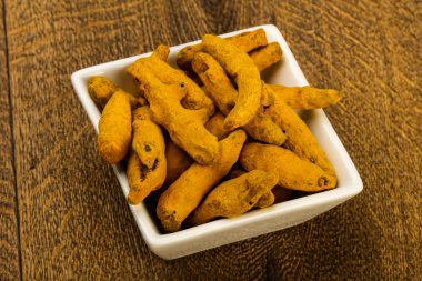 Tumeric kökü yığın içinde kase ahşap arka plan üzerinde 