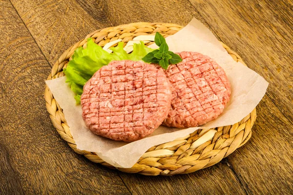 Raw burger cutlet with salad leaves ready for grill