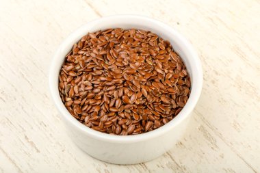 Kızartma keten tohumları ahşap arka planda kasede yığılıyor.