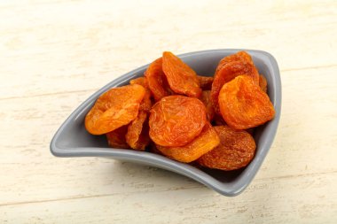 Kuru Kayısı yığın içinde kase ahşap arka plan üzerinde 