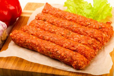 Ahşap arka plan üzerinde çiğ Dana sosis ızgara