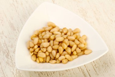 Sedir fındık yığın içinde kase ahşap arka plan üzerinde 