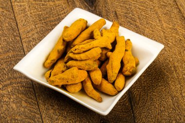 Tumeric kökü yığın içinde kase ahşap arka plan üzerinde 