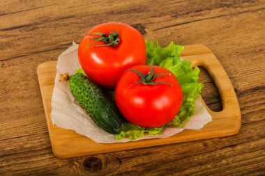 Salatalık ve domates salatası ile ahşap arka plan üzerinde bırakır