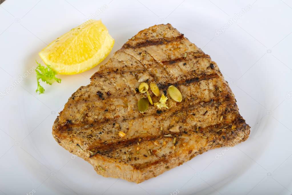 Grilled tuna steak served lemon on white plate