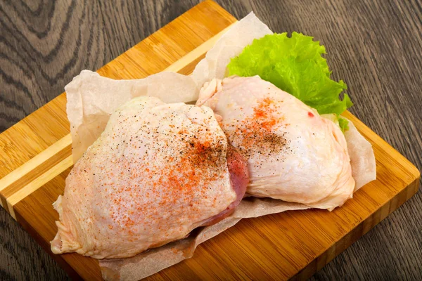 Raw chicken thighs ready for cooking over wooden background