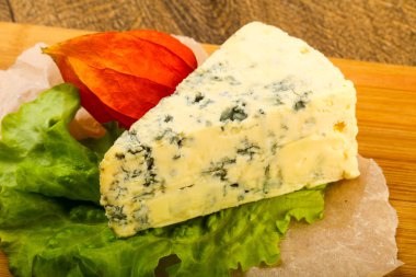 Ahşap arka planda salata yapraklı mavi peynir.