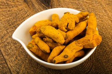 Tumeric kökü yığın içinde kase ahşap arka plan üzerinde