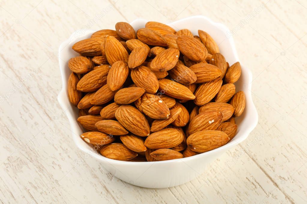 Almond in the bowl over the wooden background