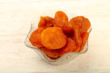 Kuru Kayısı yığın içinde kase ahşap arka plan üzerinde