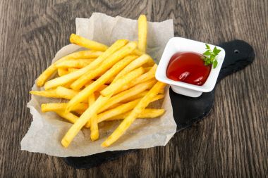French fries with tomato ketchup over wooden background
