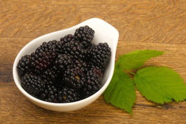 Böğürtlen yaprağı ahşap arka plan üzerinde beyaz plaka