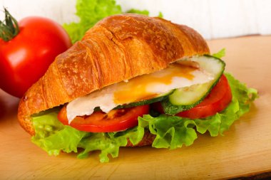 Kruvasan tavuk ve ahşap arka plan üzerinde domates ile