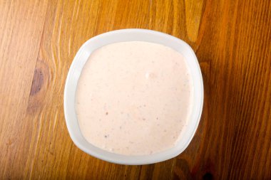 Ahşap arka plan üzerinde beyaz tabak içinde otlar ile beyaz sos