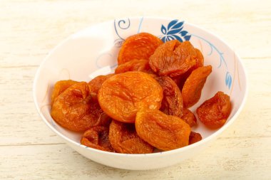 Kuru Kayısı yığın içinde kase ahşap arka plan üzerinde