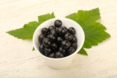 Olgun siyah kuş üzümü ile yaprak kase