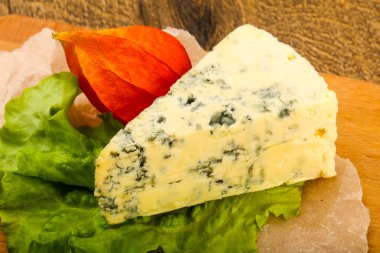 Ahşap arka planda salata yapraklı mavi peynir.