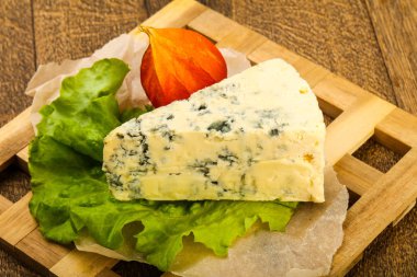 Ahşap arka planda salata yapraklı mavi peynir.