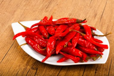Ahşap arka plan üzerinde beyaz tabakta chili biber turşusu