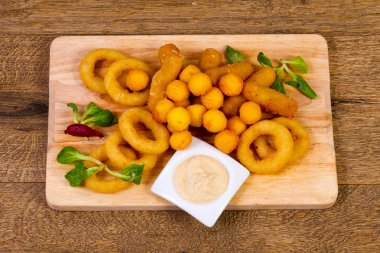 Soğan halkaları ve patates topları ahşap arka plan üzerinde yavru