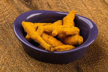 Tumeric kökü yığın içinde kase ahşap arka plan üzerinde