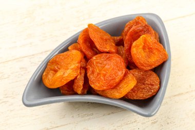 Kuru Kayısı yığın içinde kase ahşap arka plan üzerinde