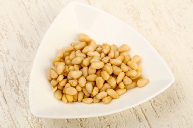 Sedir fındık yığın içinde kase ahşap arka plan üzerinde