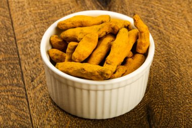 Tumeric kökü yığın içinde kase ahşap arka plan üzerinde