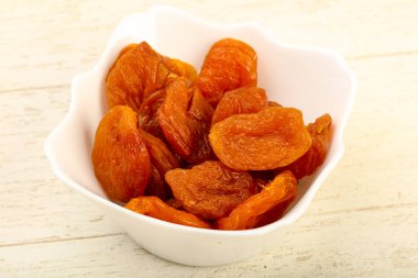 Kuru Kayısı yığın içinde kase ahşap arka plan üzerinde