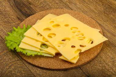 Ahşap arka plan üzerinde dilimlenmiş peynir salata yaprakları