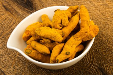 Tumeric kökü yığın içinde kase ahşap arka plan üzerinde