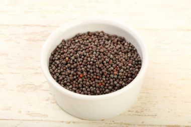 Kase ahşap arka plan üzerinde siyah hardal tohumu yığın