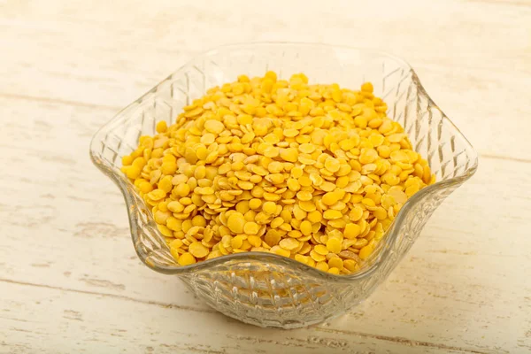 Yellow lentil ready for cooking over wooden background